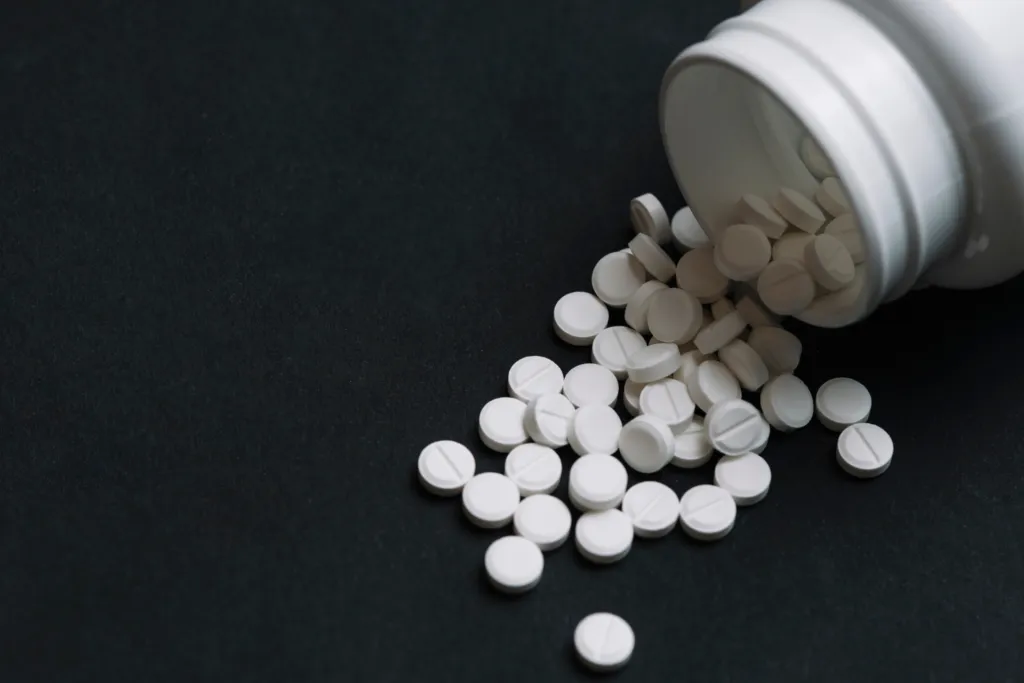 White disulfiram tablets spilled from a prescription bottle