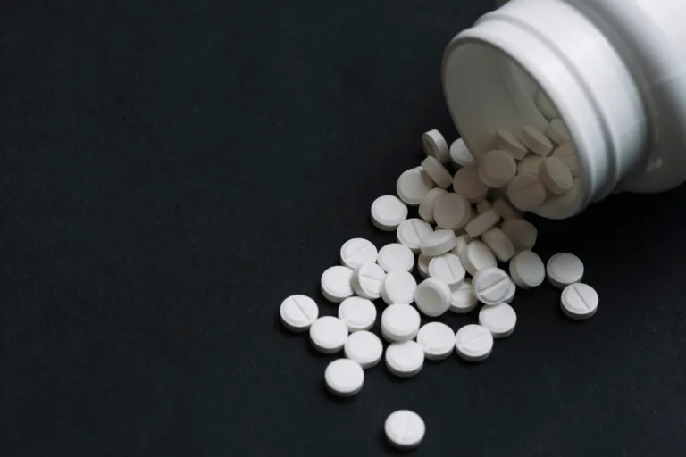 White disulfiram tablets spilled from a prescription bottle